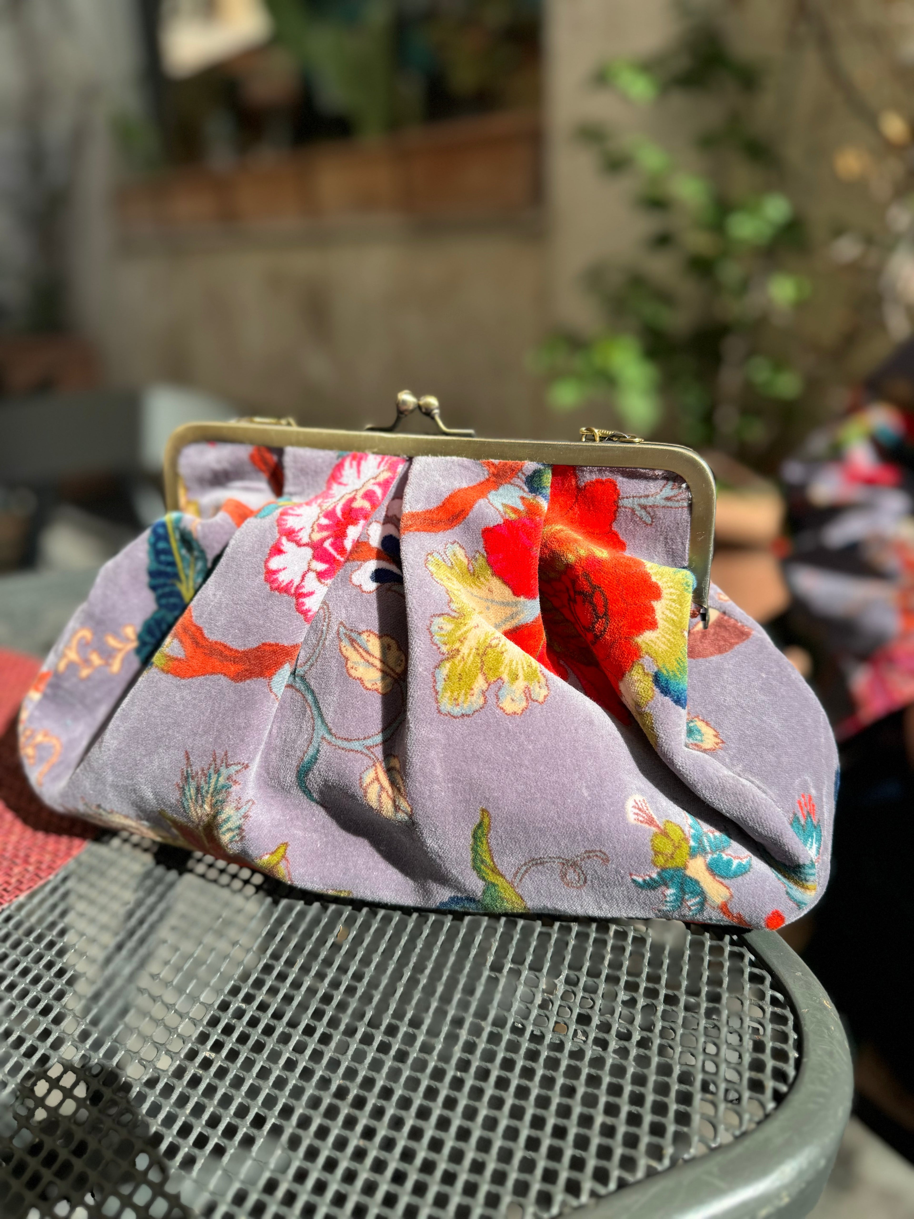 Borsetta estiva in cotone stampato a mano con fantasia floreale rosa su sfondo arancione tenuta in mano